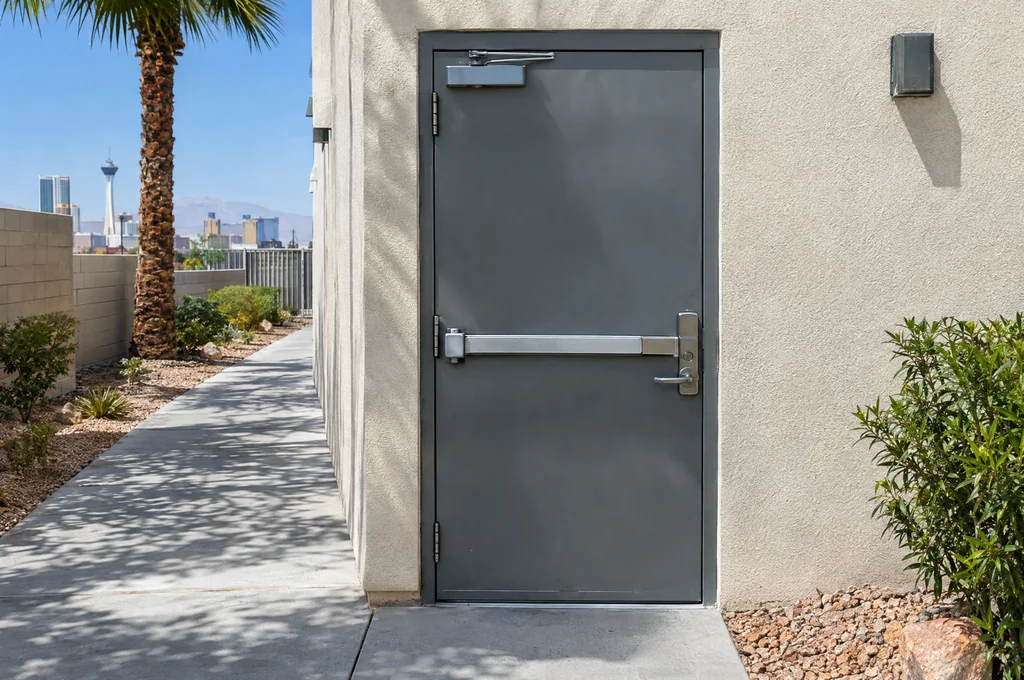 Commercial exit door with a push bar and palm trees outside, for business locksmith questions in Las Vegas